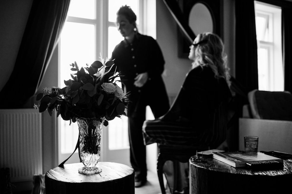 Black and white candid moment with elegant floral arrangement in the foreground.
