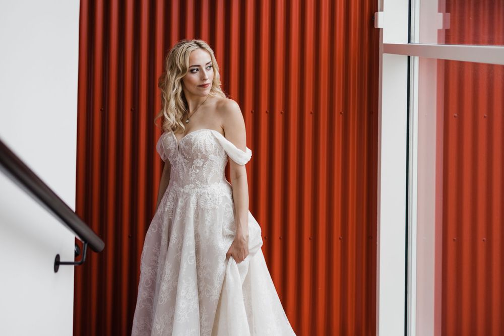 Wedding dress against red corrugated wall with staircase railing.