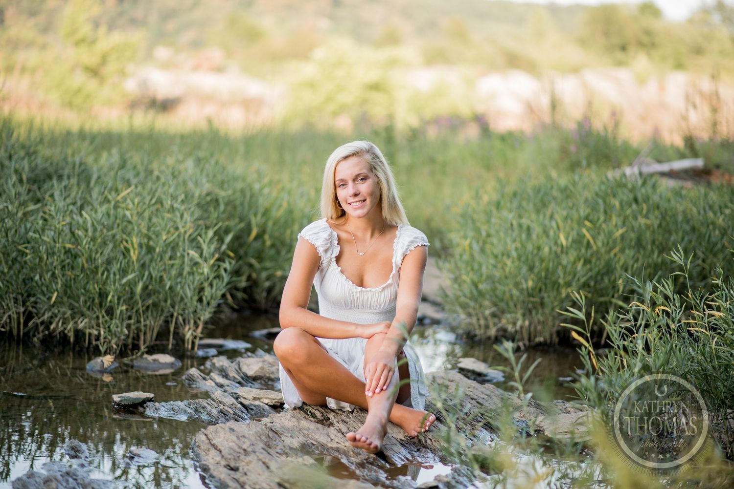 A summer portrait session near a pond with tall grass and natural lighting.