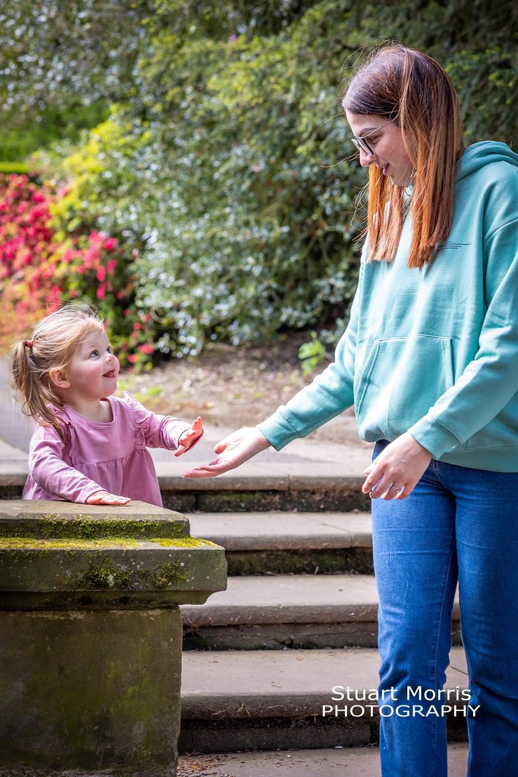 mum puts her hand out to her young daughter. informal portrait session. Stuart Morris Photography.