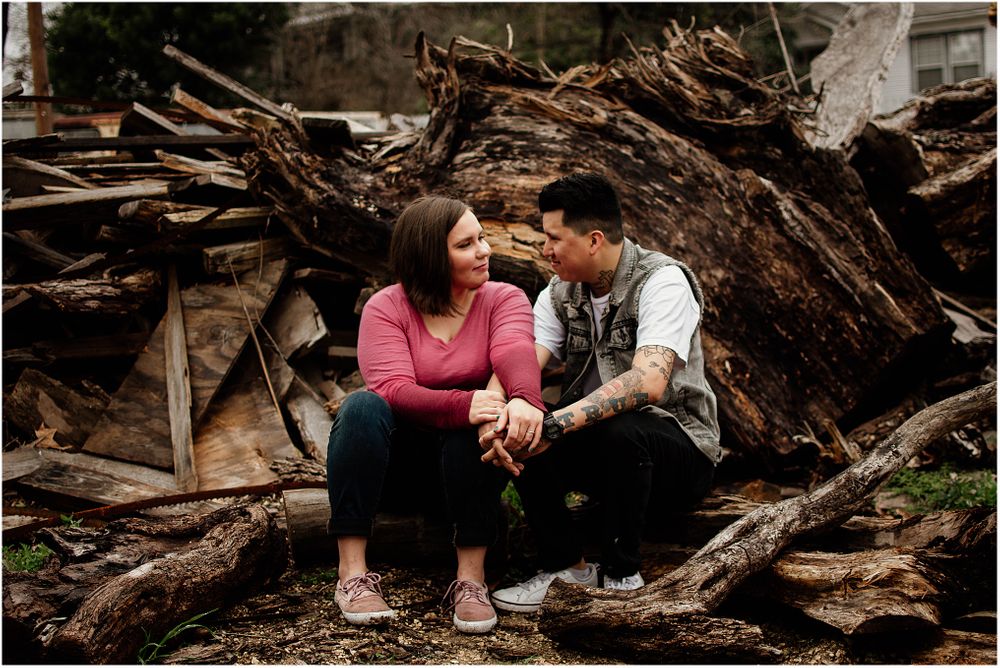 A couple shares an intimate moment while sitting on a pile of logs.