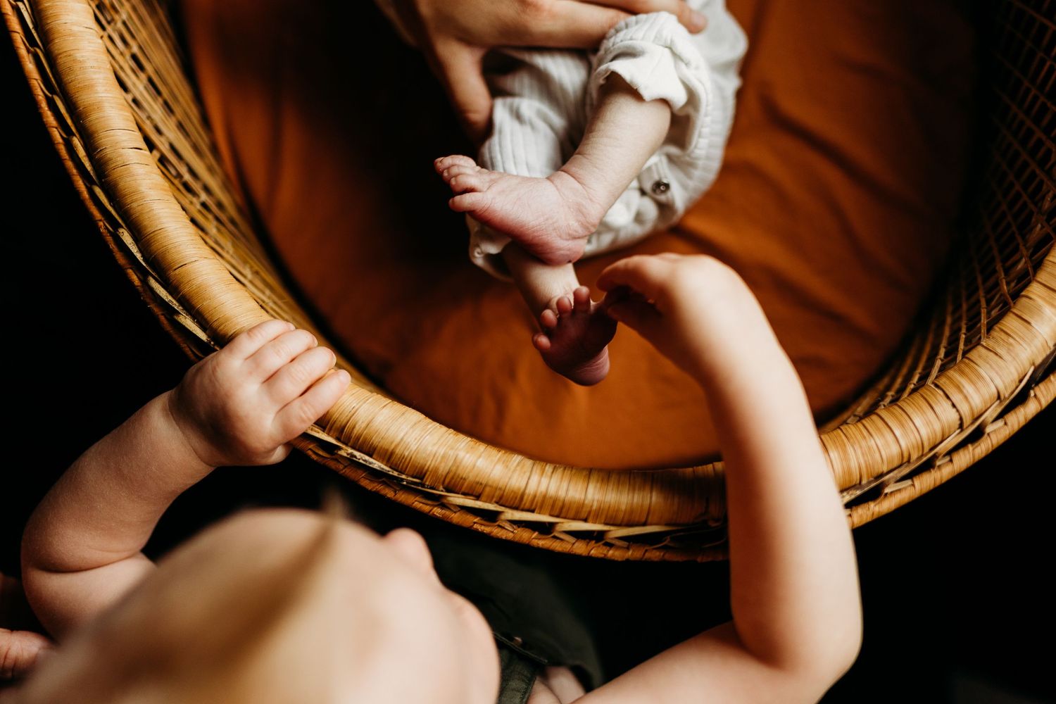 An overhead view of a baby lying in a woven rattan bassinet.