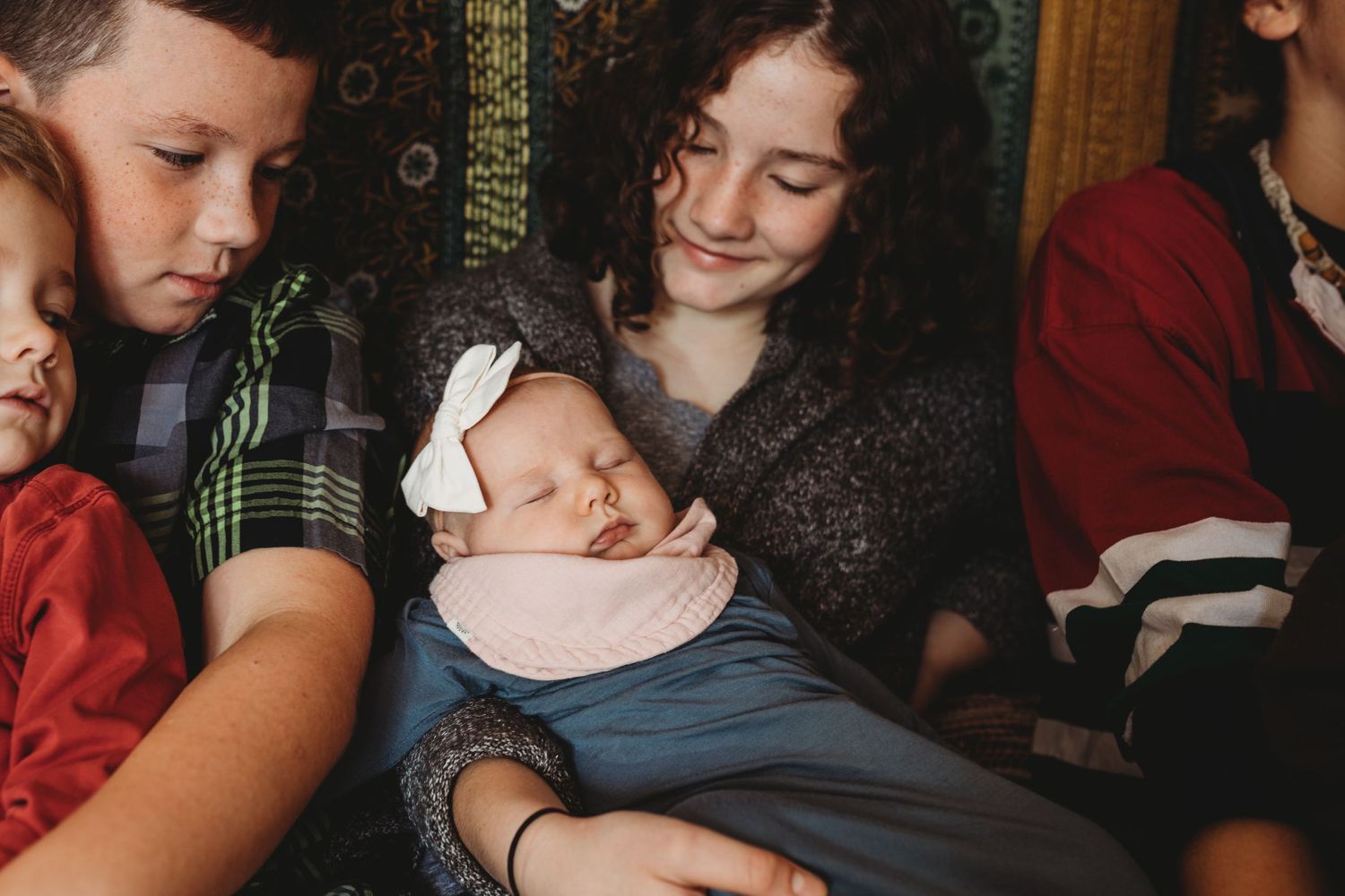 Big sister holds baby sister next to brothers