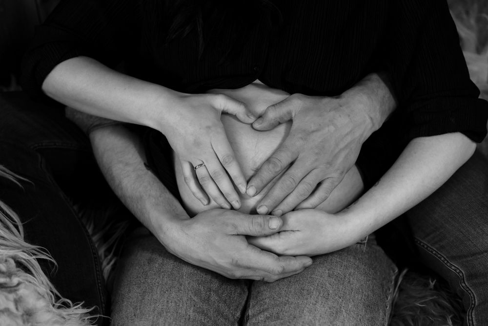 Artistic black and white photograph showing interlinked hands in soft lighting.