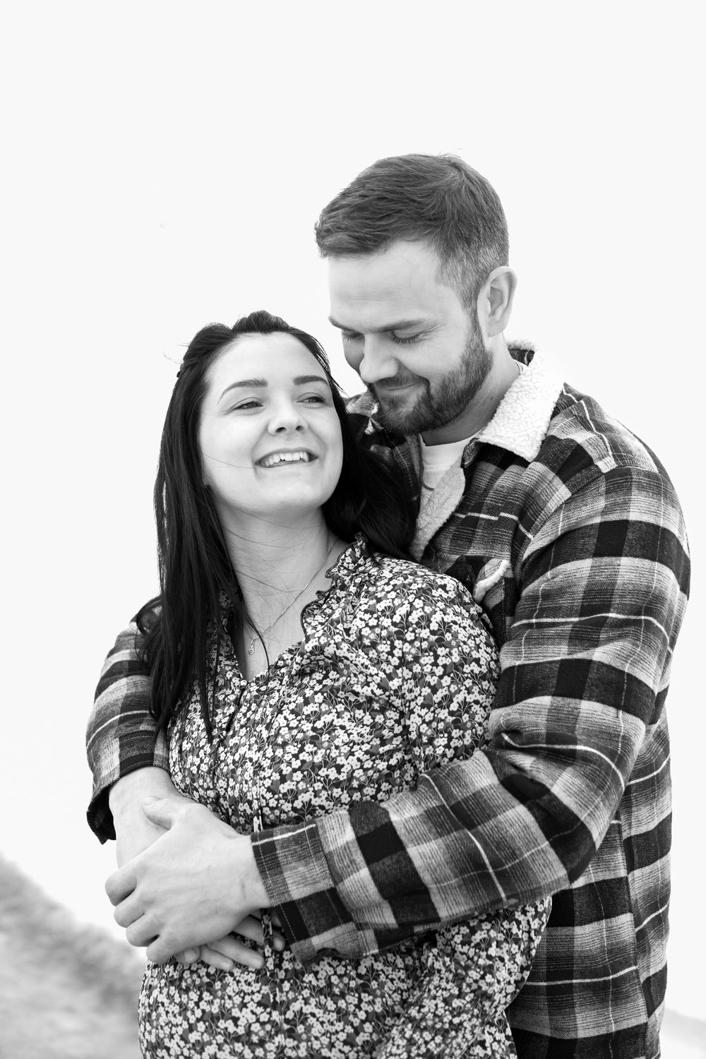 Romantic couple embracing in winter wear against white background.
