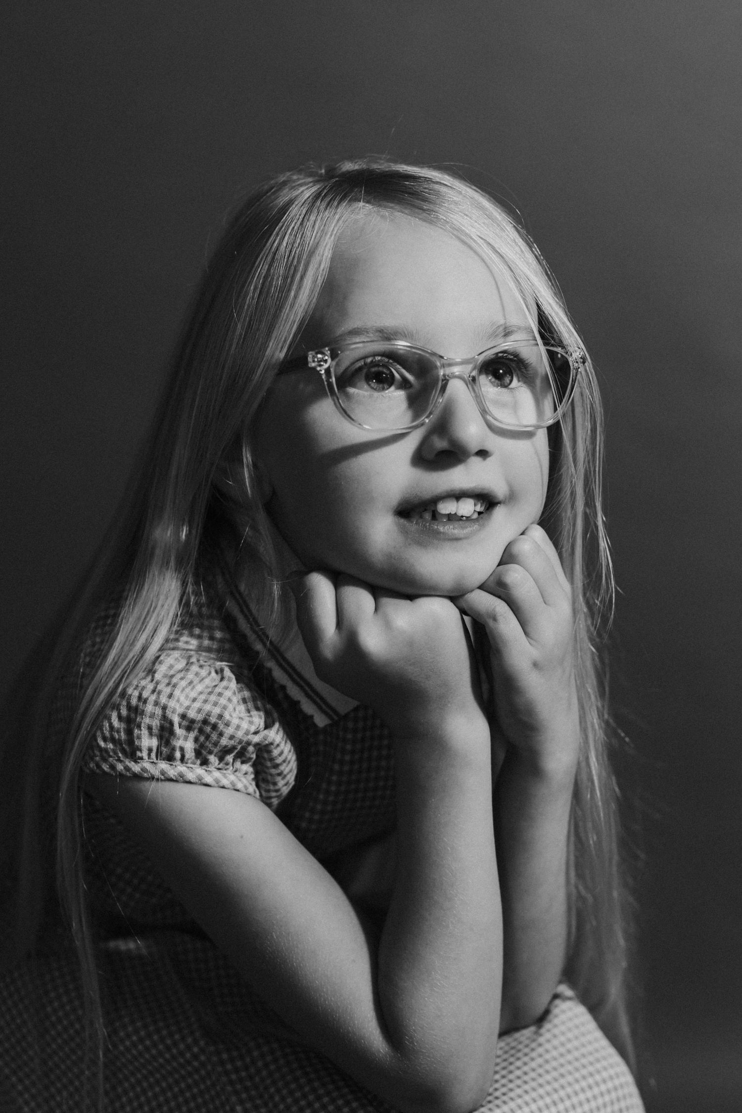 Black and white portrait of young person in glasses with thoughtful pose.