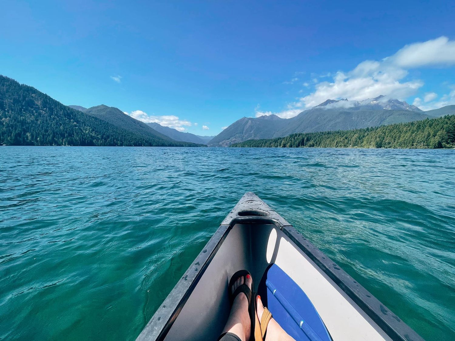 Scenic kayaking adventure through turquoise waters surrounded by forested mountains and blue skies.
