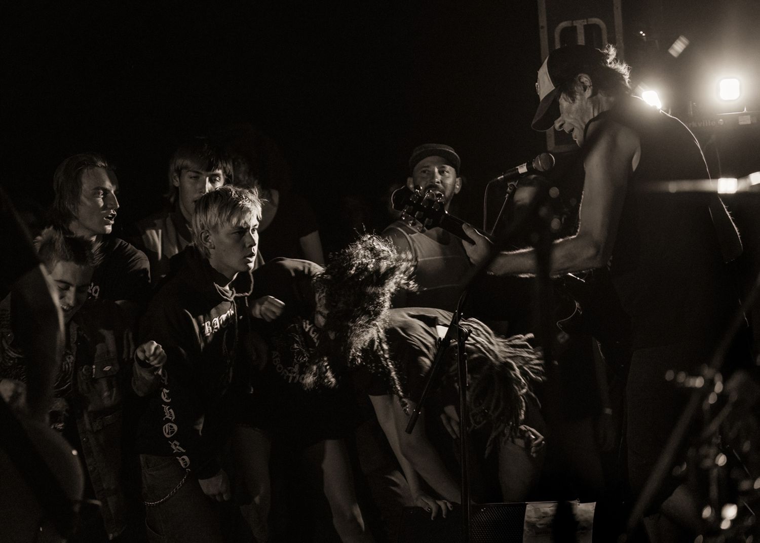 Black and white photo of crowded concert audience watching performers on stage.