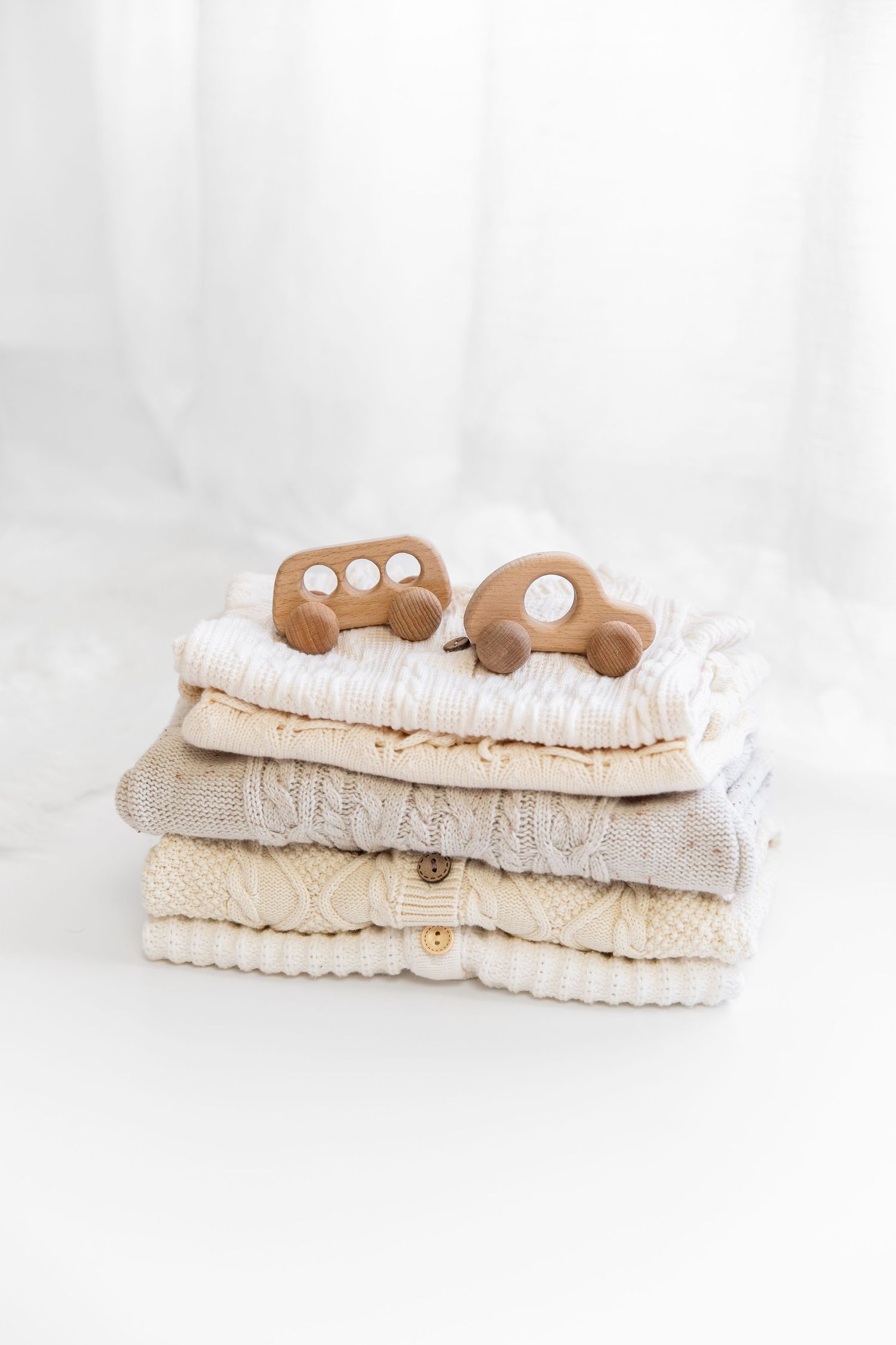Folded knit baby clothing with wooden toys on top