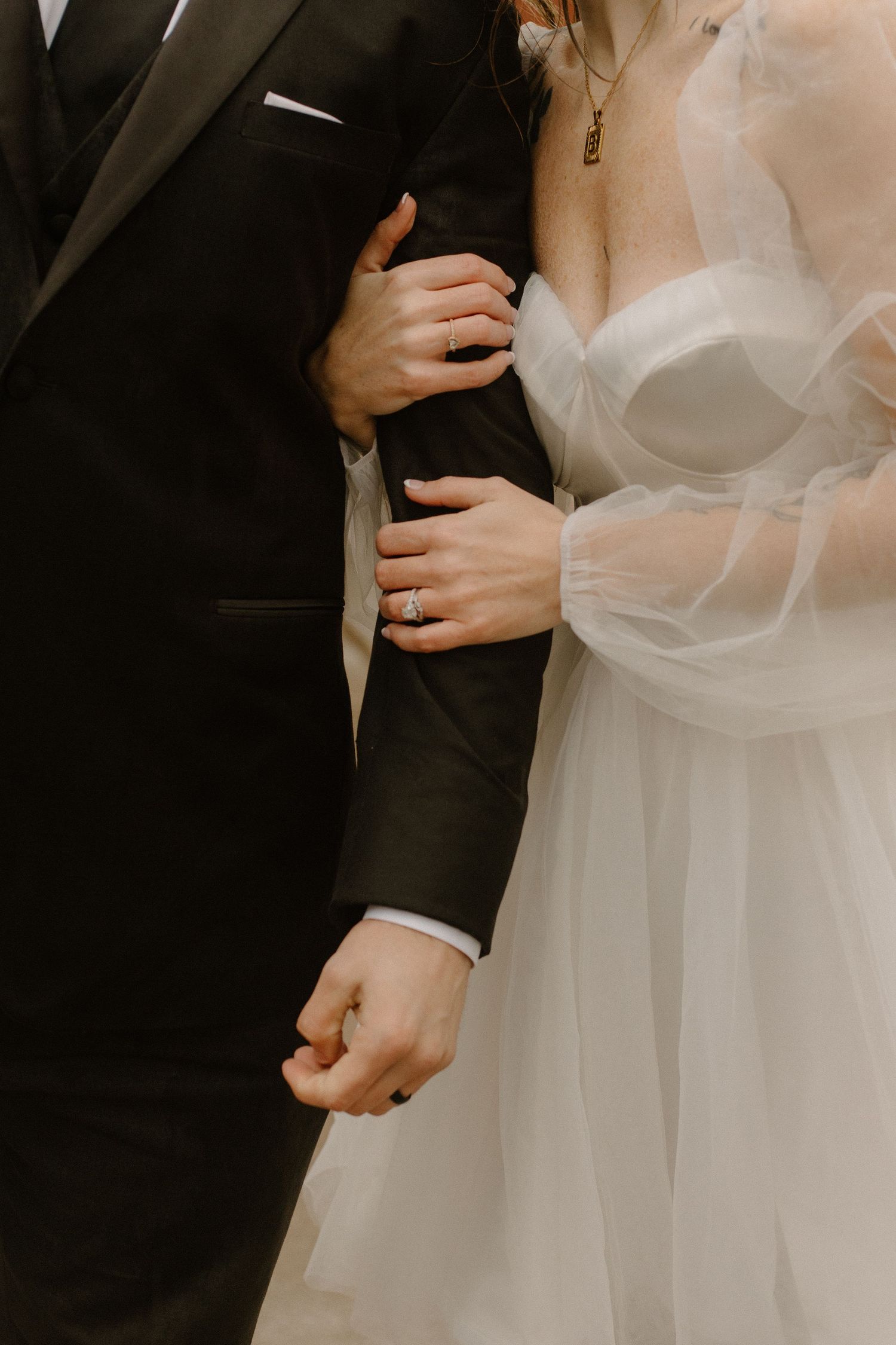 Intimate close-up of couple's hands and torsos in wedding attire showing delicate details.