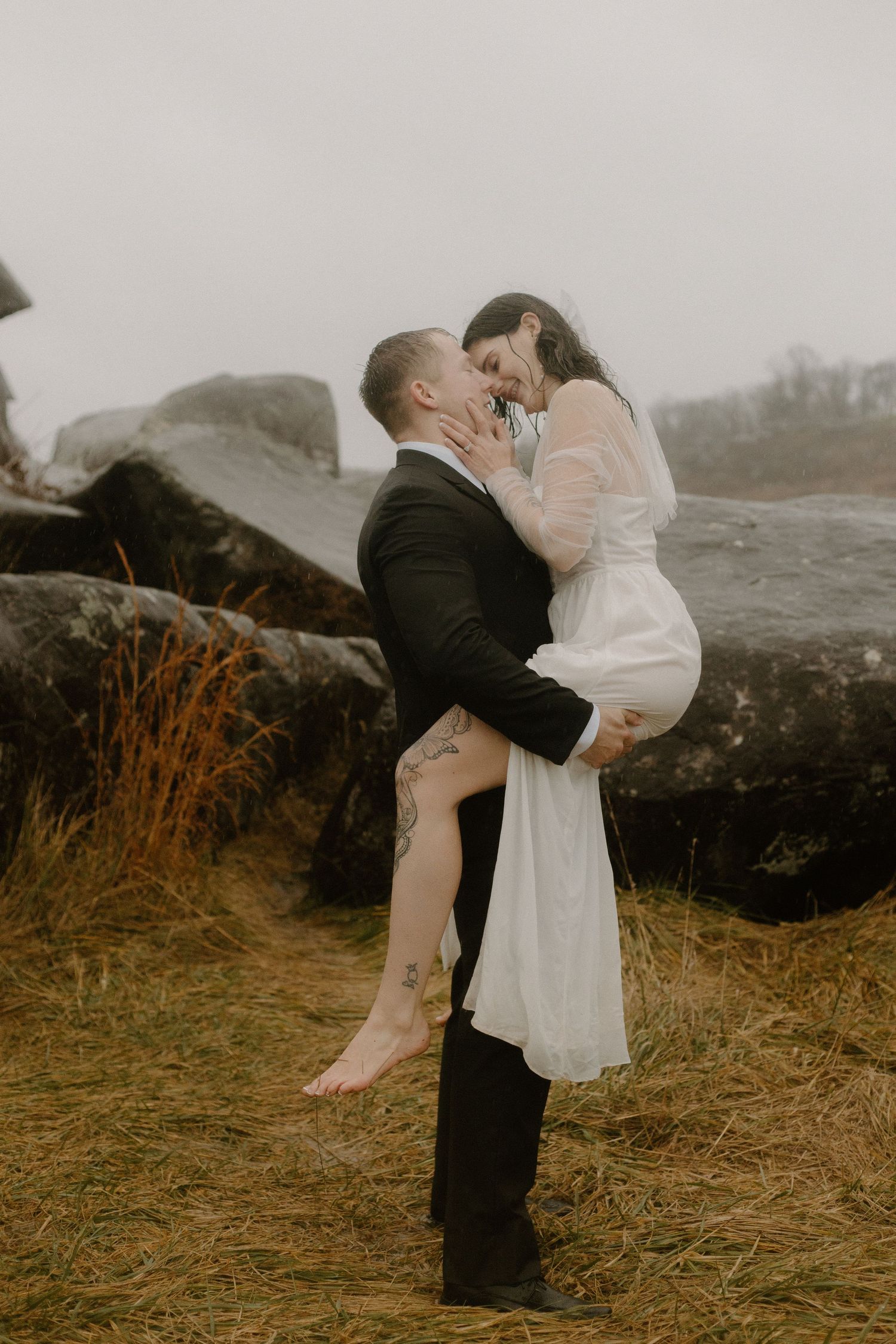 An intimate wedding portrait with the couple embracing against a backdrop of rocky terrain.