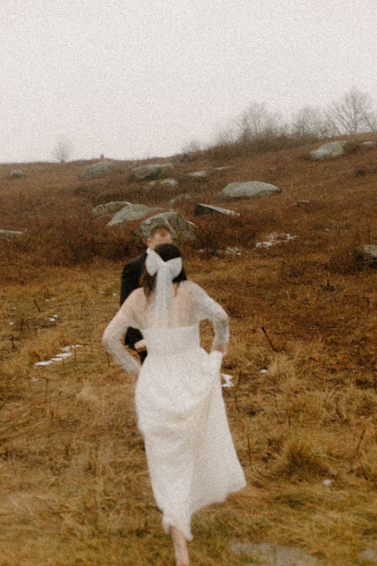 Vintage photo of a person in a white dress standing on a hillside with scattered rocks.