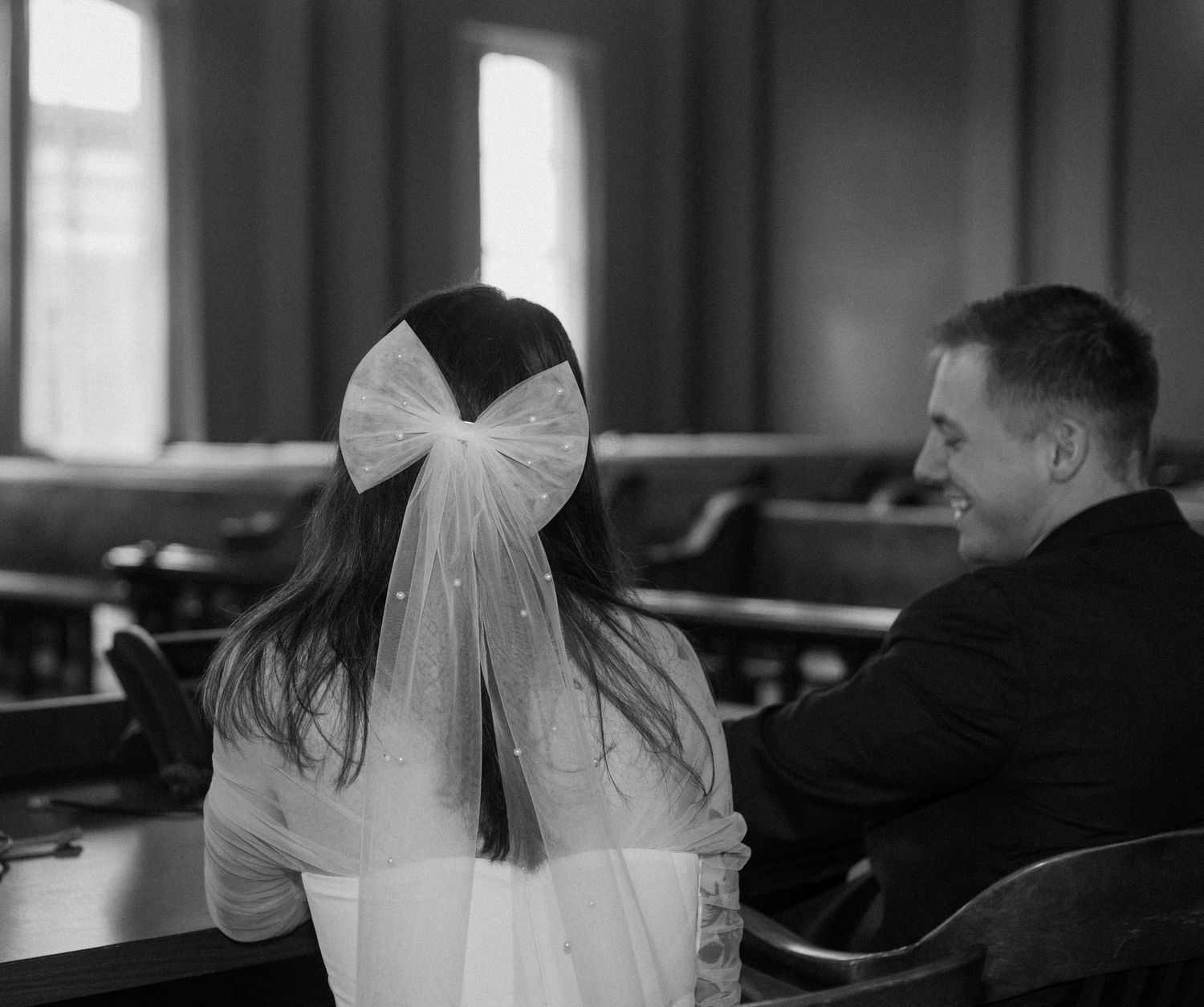 A view from behind of a couple sitting in church pews.