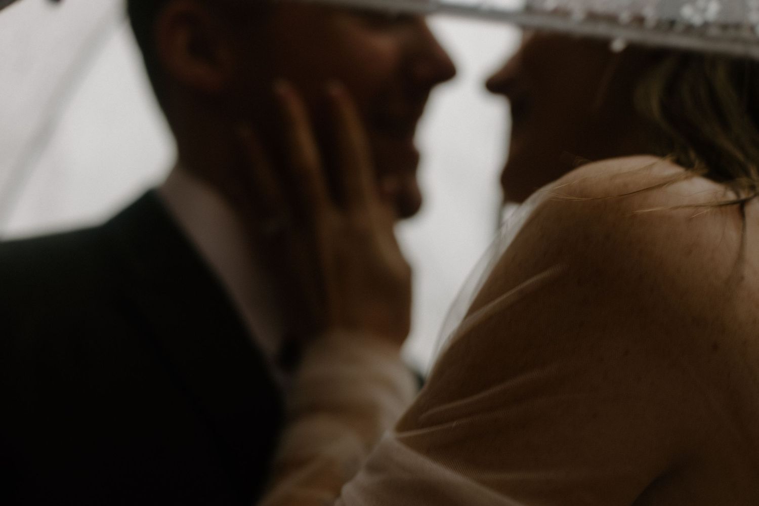 A blurred artistic wedding photograph in muted tones showing intimate close-up details.