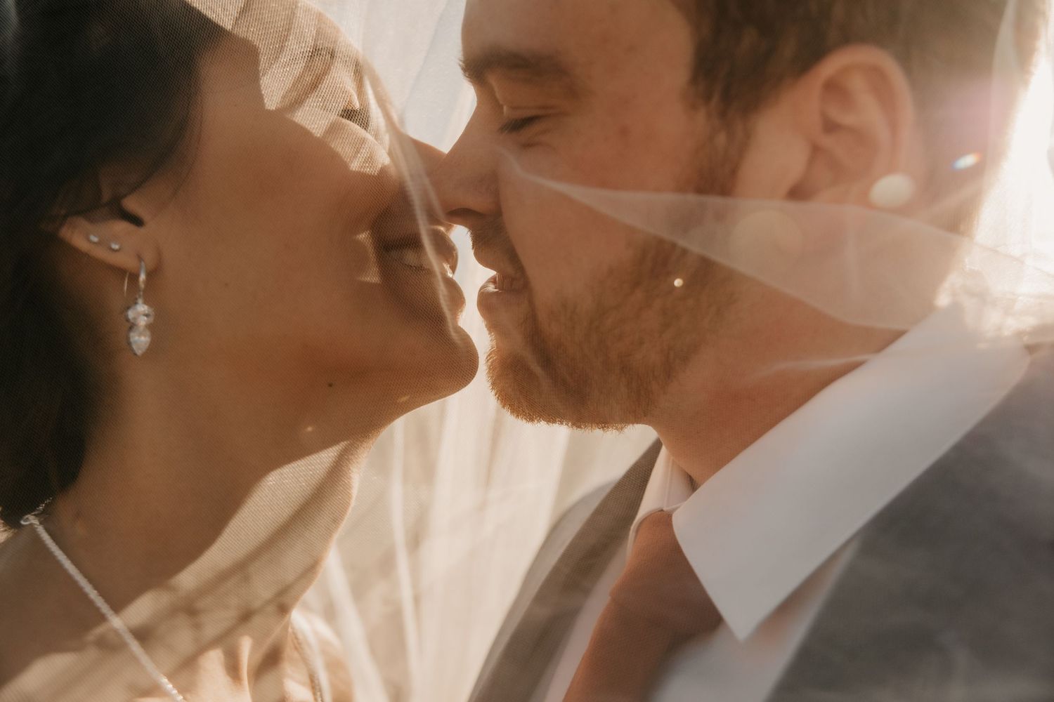 Close up shot of a romantic wedding couple in soft sunlight sharing an intimate moment.