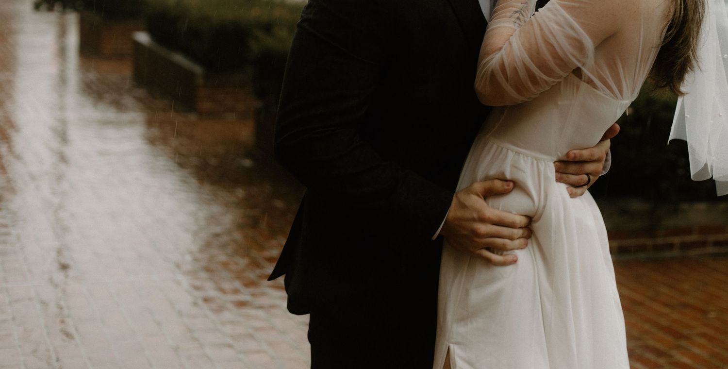 A close-up of a couple embracing outdoors near water.