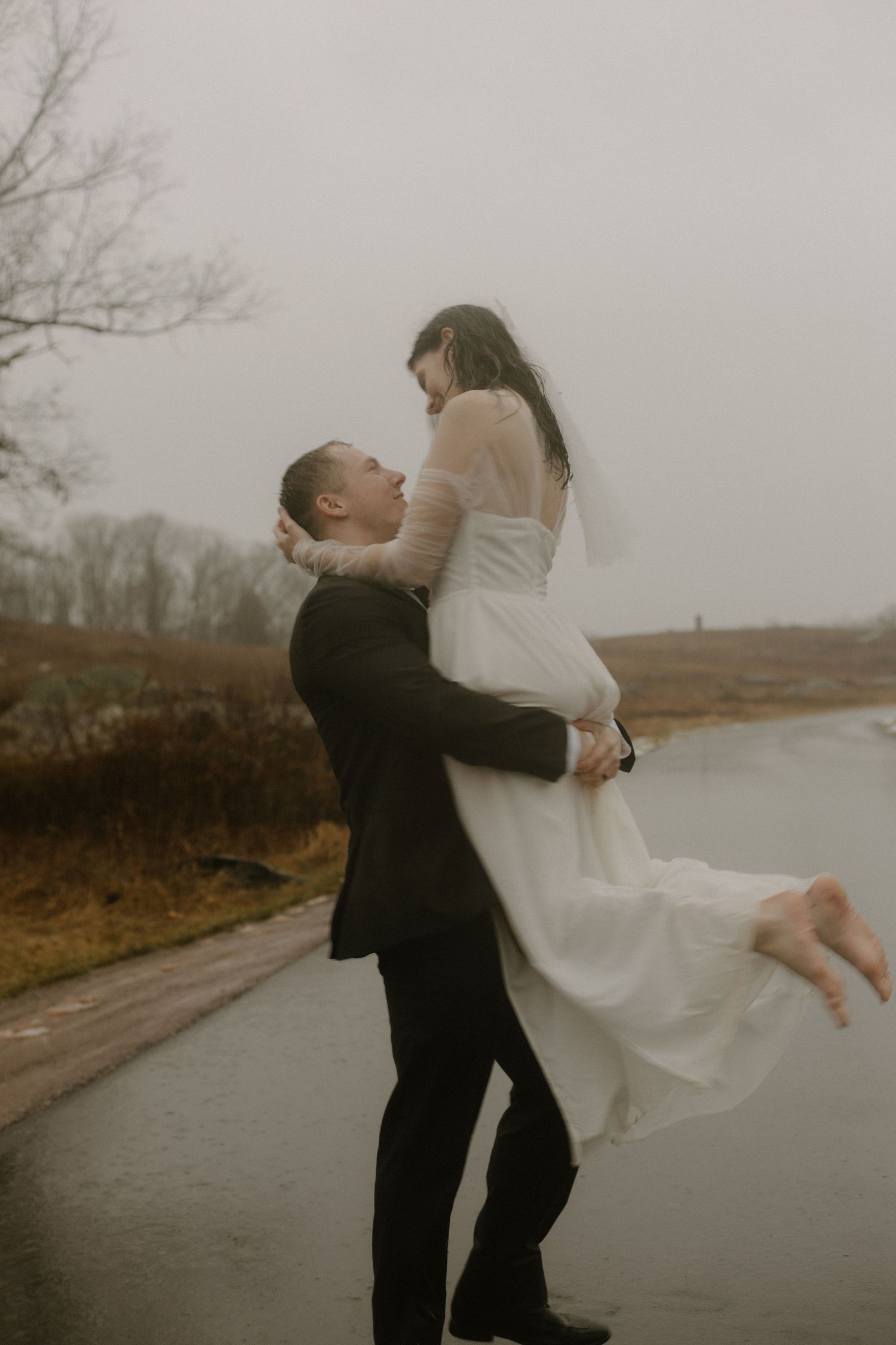 Romantic wedding lift pose on a rainy road with moody atmosphere.