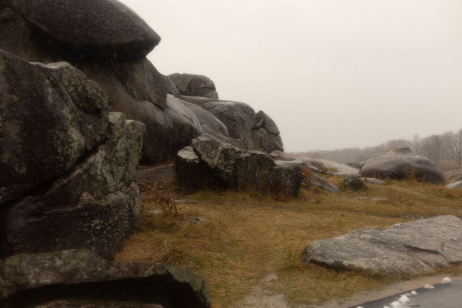 Misty landscape with large rocky boulders and overcast sky in a natural outdoor setting.