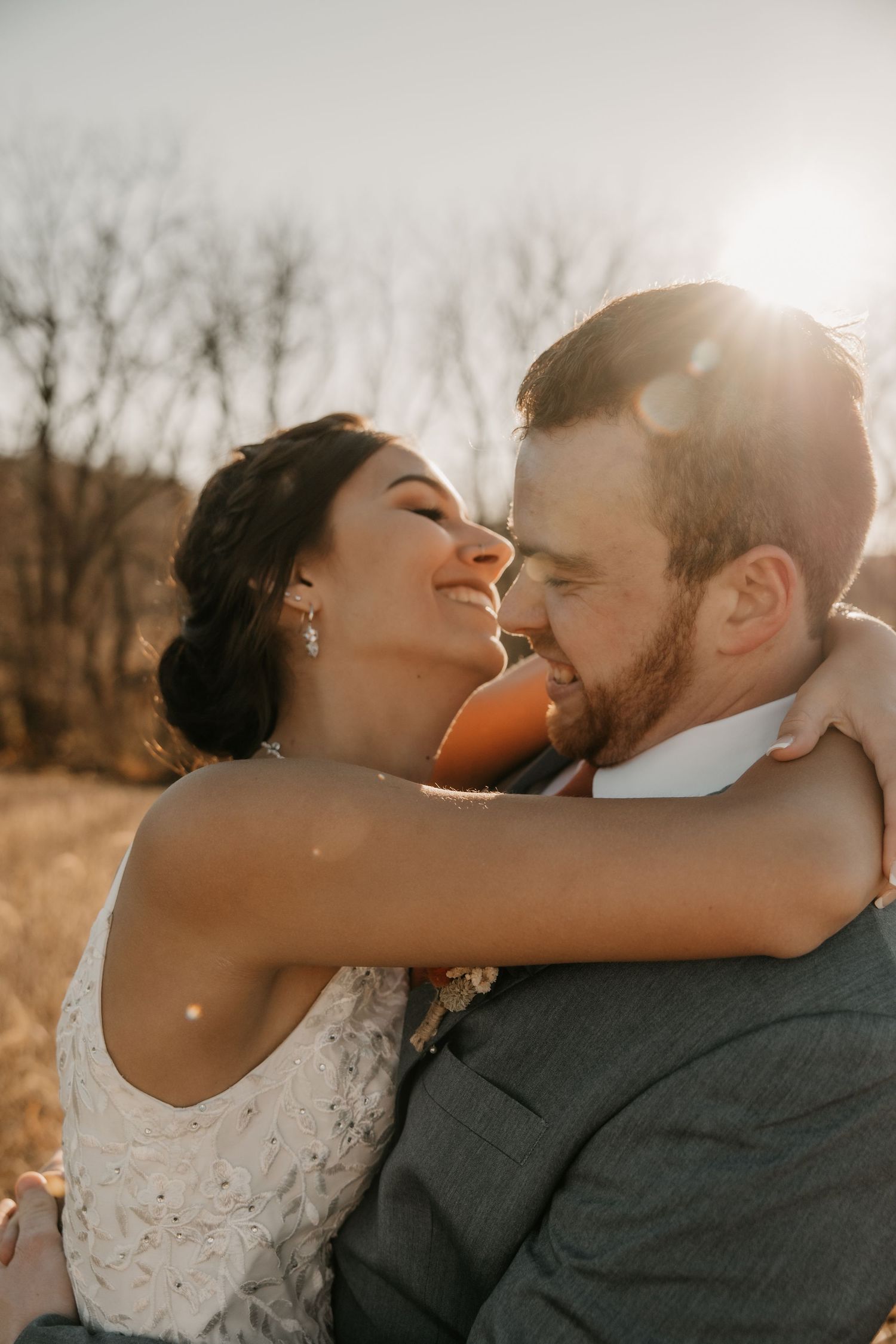 Sunlit wedding portrait of couple embracing outdoors against autumn backdrop.