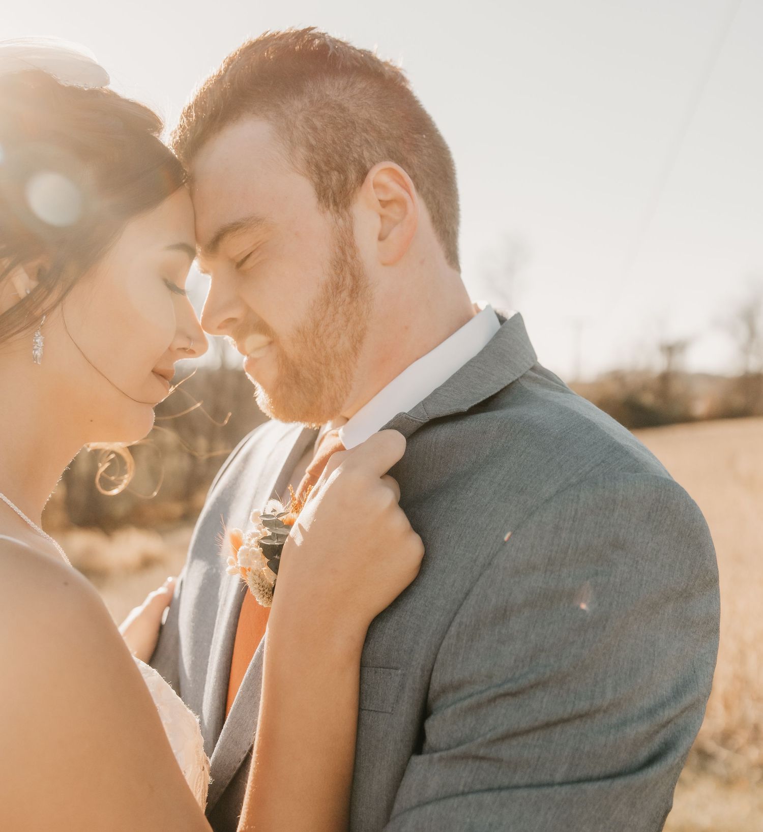 Romantic golden hour portrait of newlyweds sharing an intimate moment outdoors.