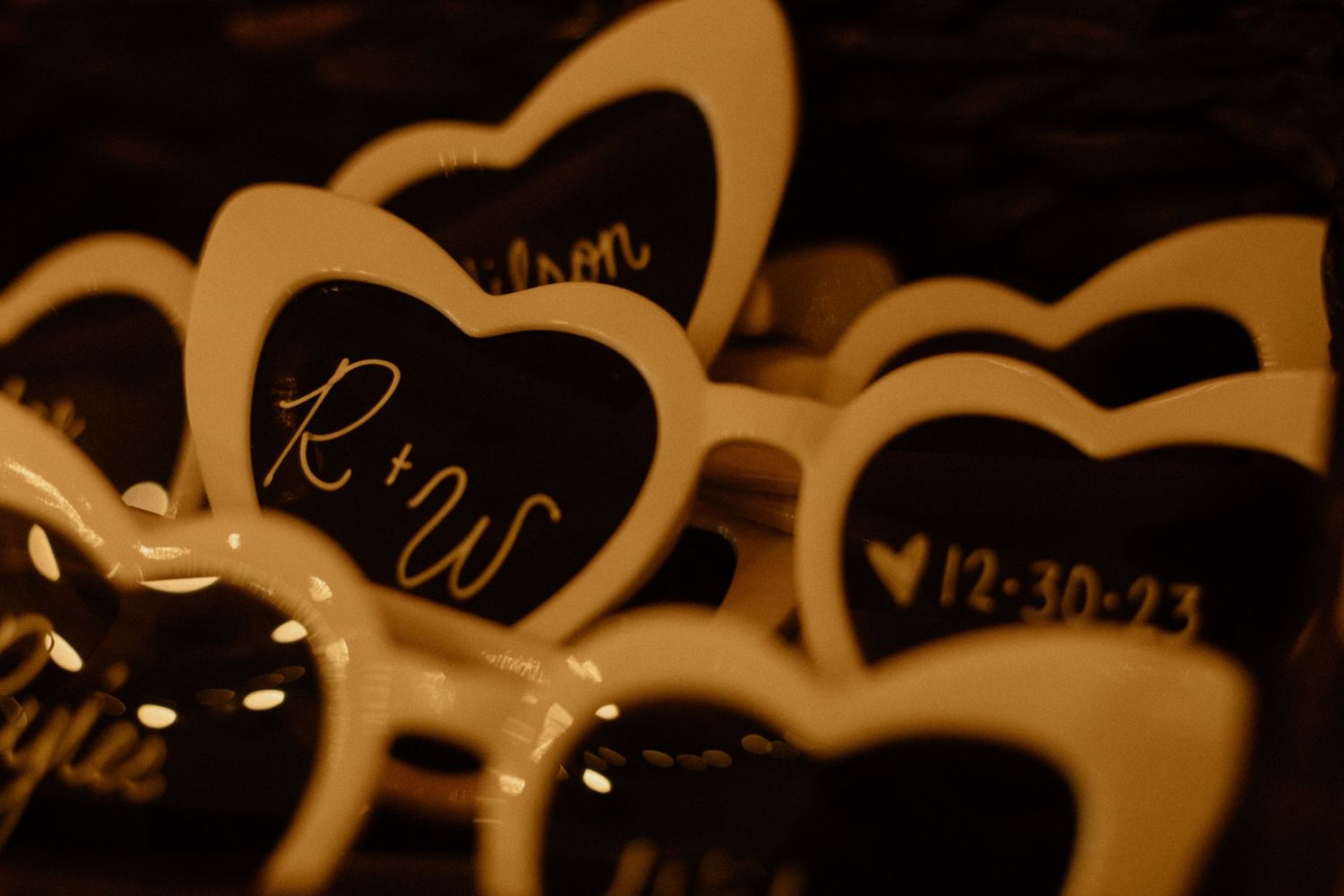 Black heart-shaped wedding signs with dates written in elegant script illuminated in warm lighting.