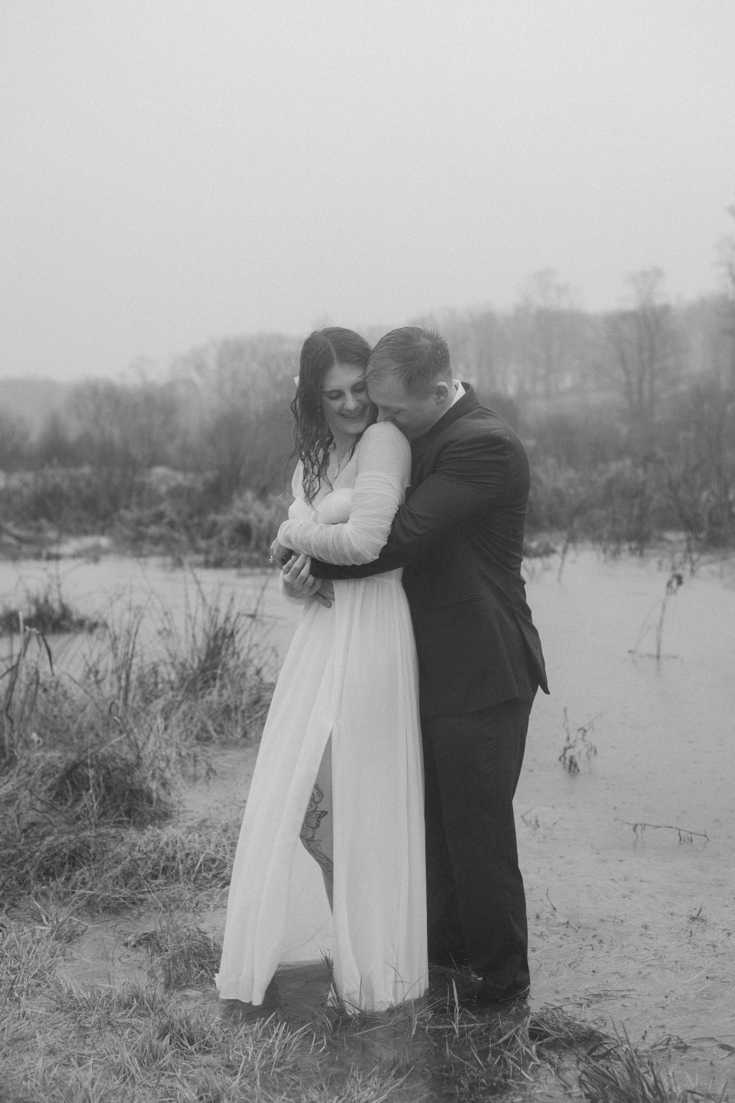 Romantic black and white wedding photo by a misty lake.