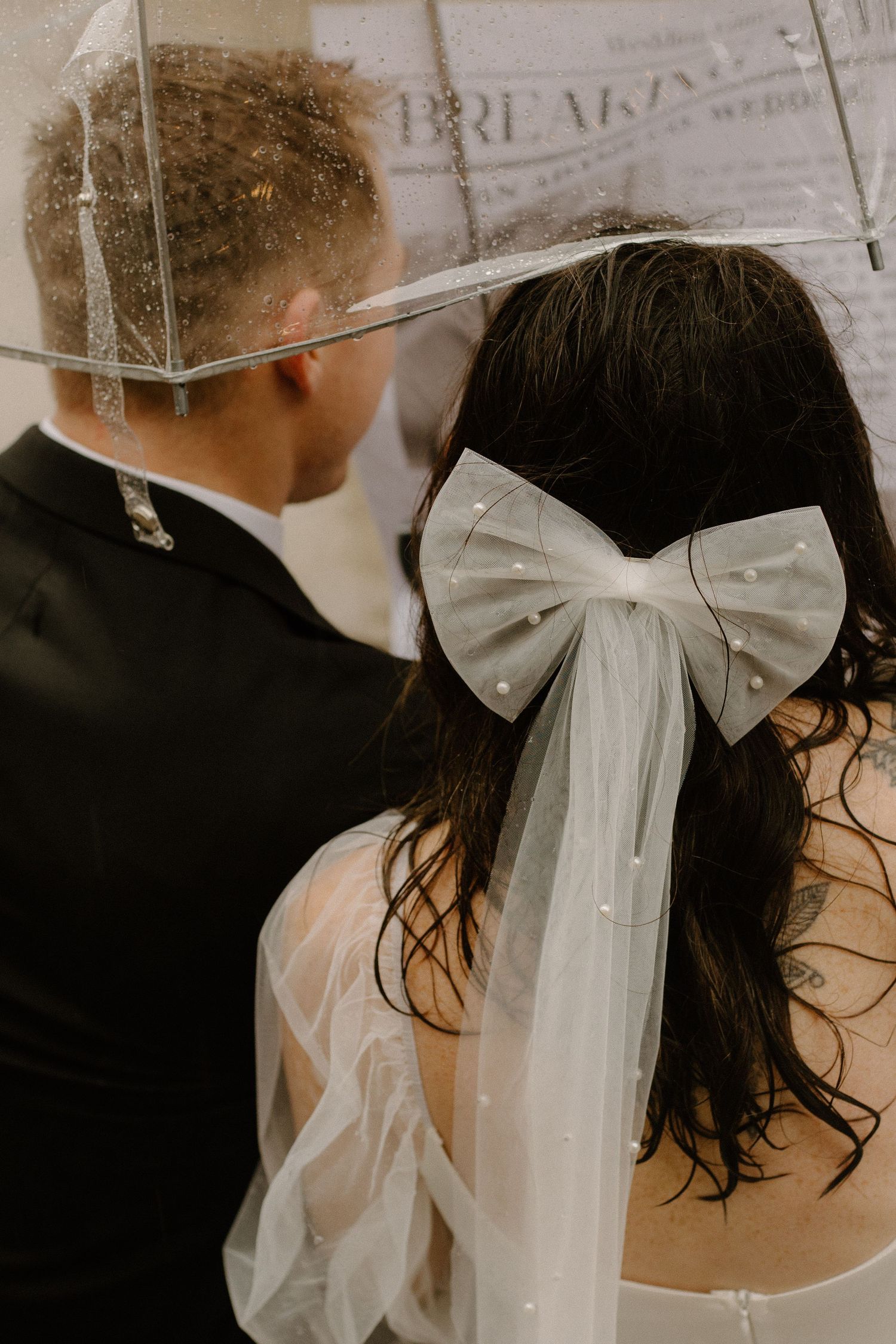 A close-up view of a wedding bow hair accessory and umbrella on a rainy day.