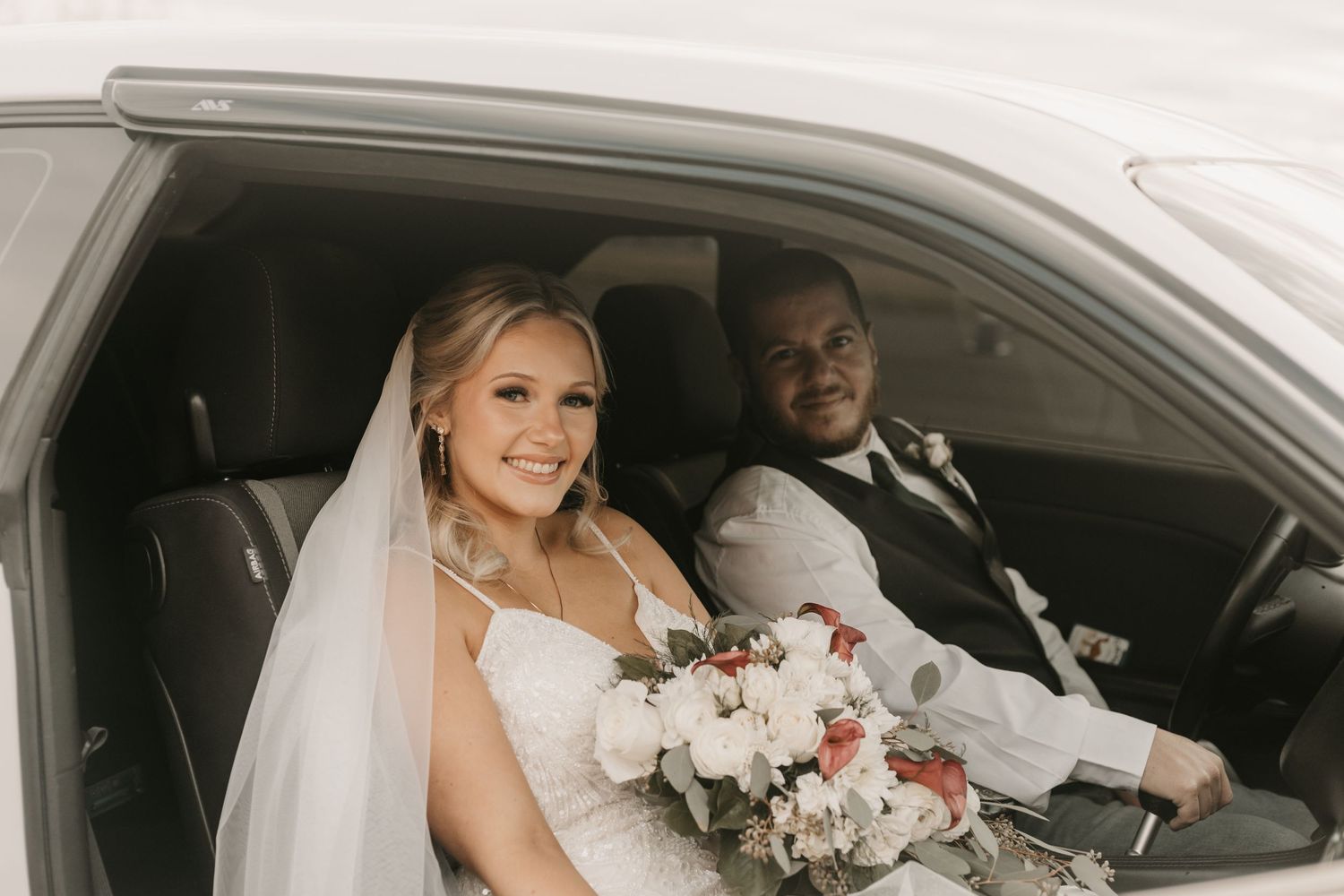 A wedding couple sharing a joyful moment in their car after the ceremony.