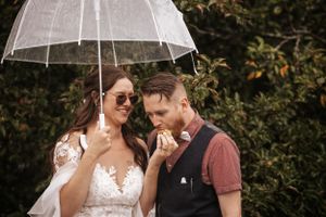 Couple sharing tender moment under clear umbrella in garden setting.