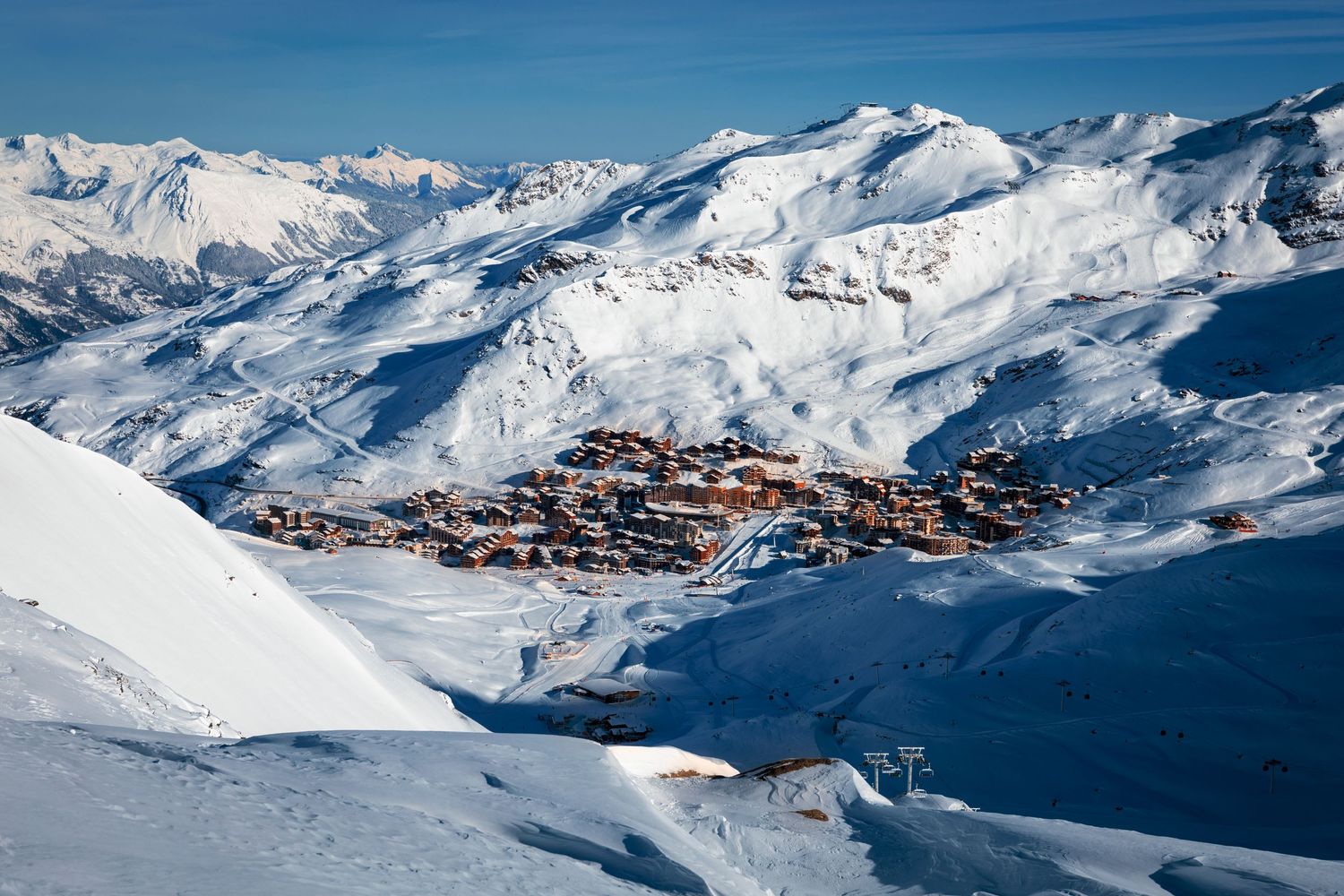 Aerial view of a snow-covered ski resort village nestled in the French Alps mountain range.