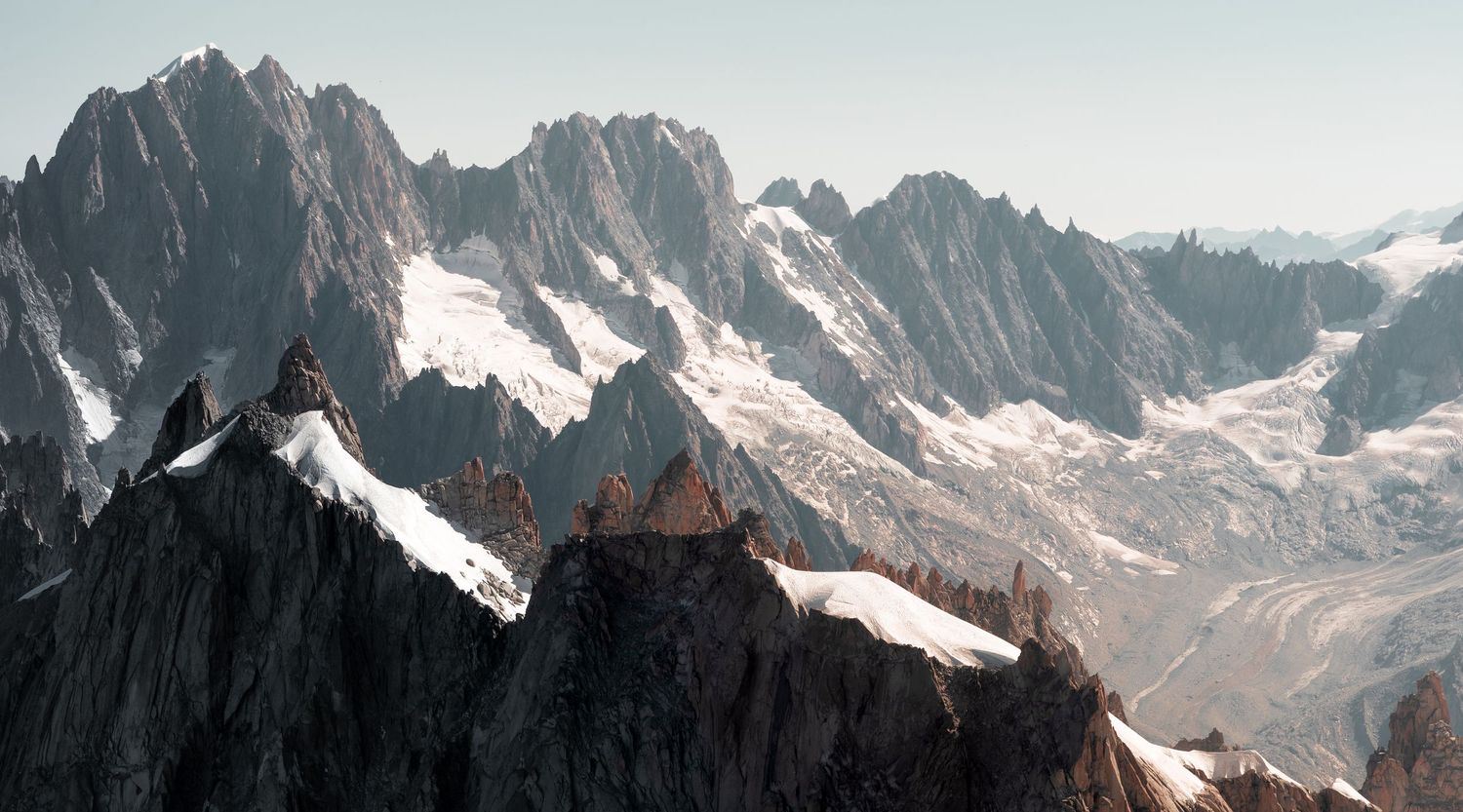 Dramatic mountain landscape with snow-capped peaks and jagged ridges in alpine terrain.