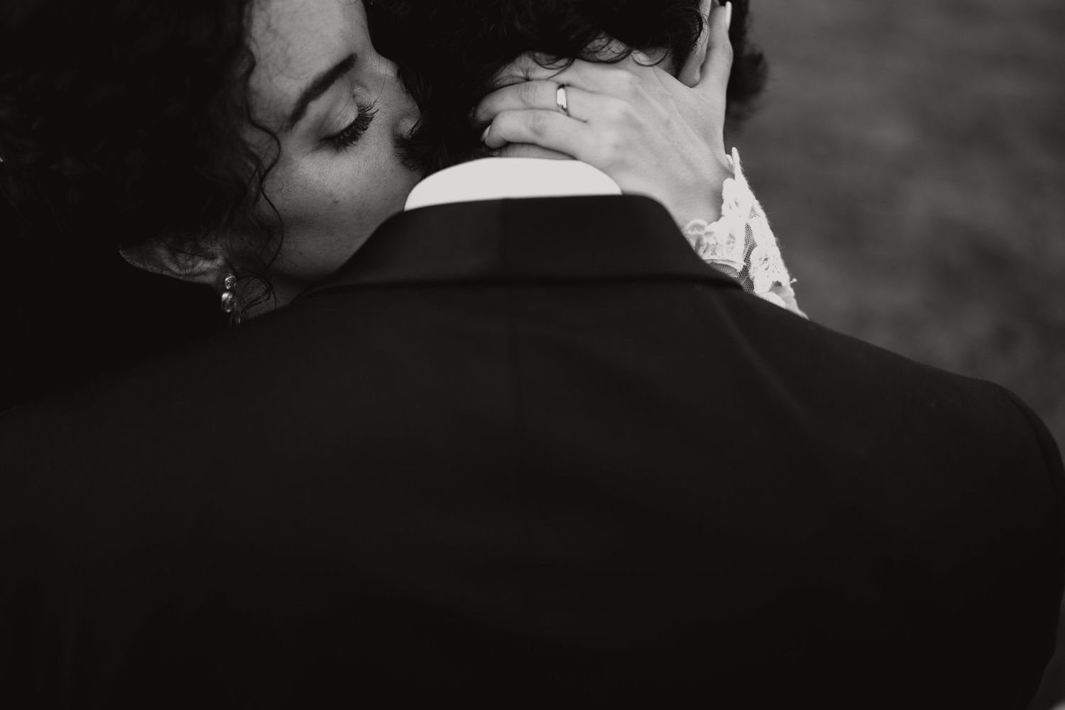 An artistic black and white close-up wedding photo capturing an intimate embrace.