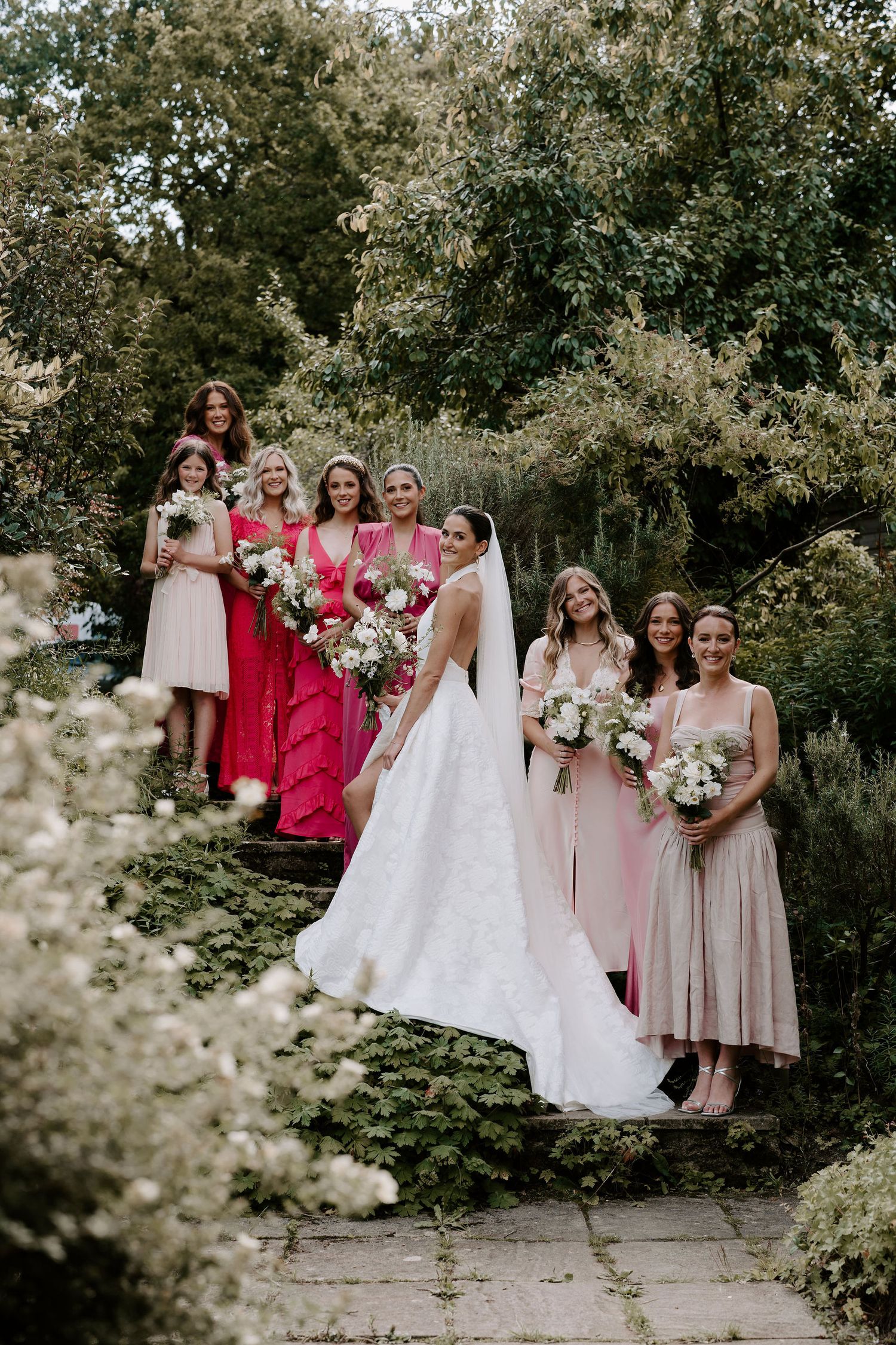 Bride and bridesmaids on steps smiling before leaving for the wedding ceremony in Oxfordshire