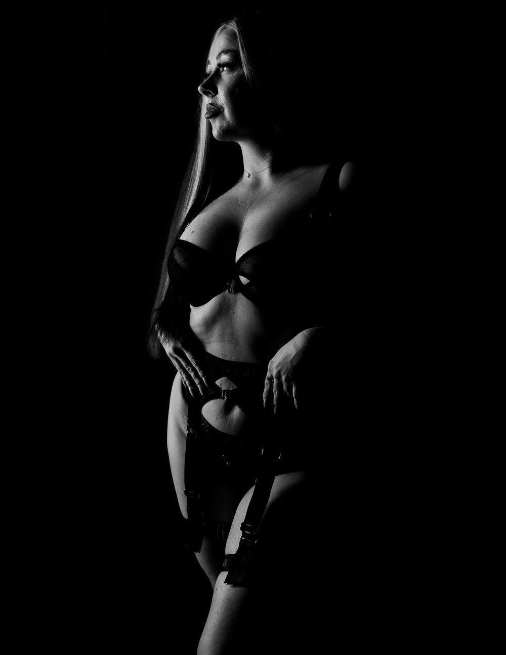 Artistic black and white boudoir photograph with dramatic shadows and contrast.