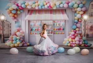Dreamy candyshop setup with pastel balloon arch and sweet treats displayed on shelving in soft pink and blue tones.