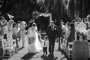 Black and white ceremony photo with guests throwing flower petals in outdoor garden setting.