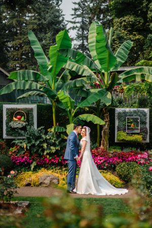 Romantic garden wedding scene with large banana leaves and pink flowers framing an elegant archway.