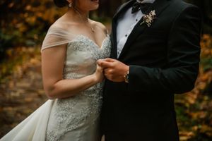 Close-up detail of formal wedding attire against autumn foliage background.