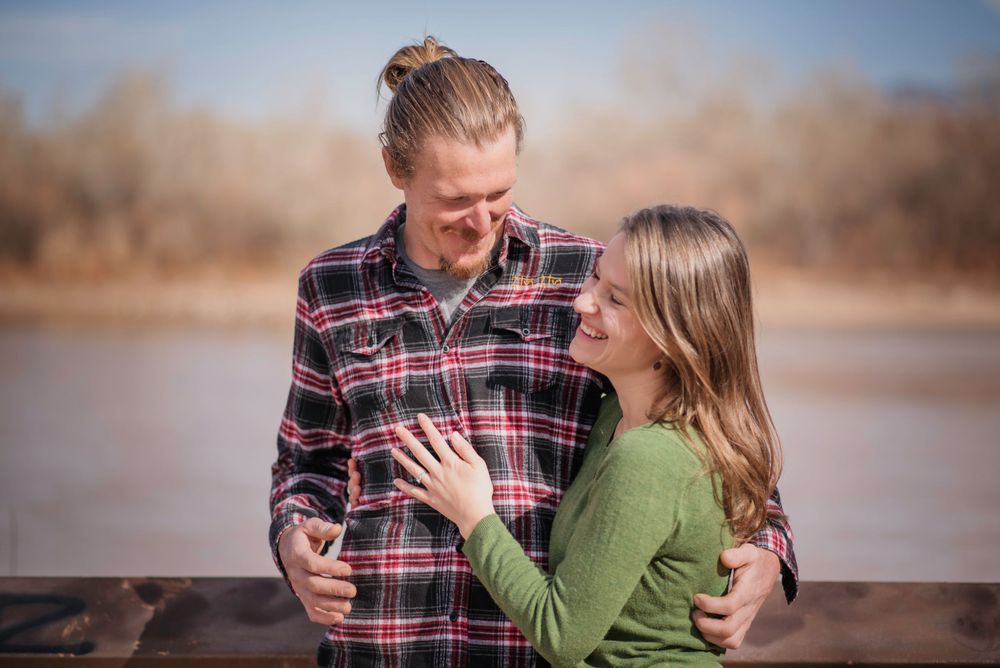Couple laughing in front of river, embracing one another.