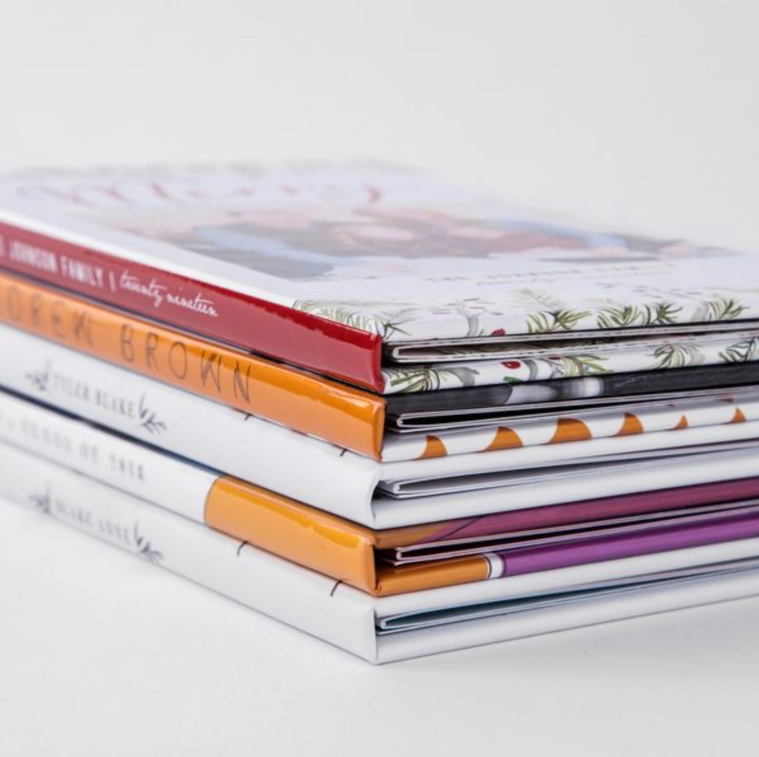 Stack of professional photo albums with varying spine colors and thicknesses.