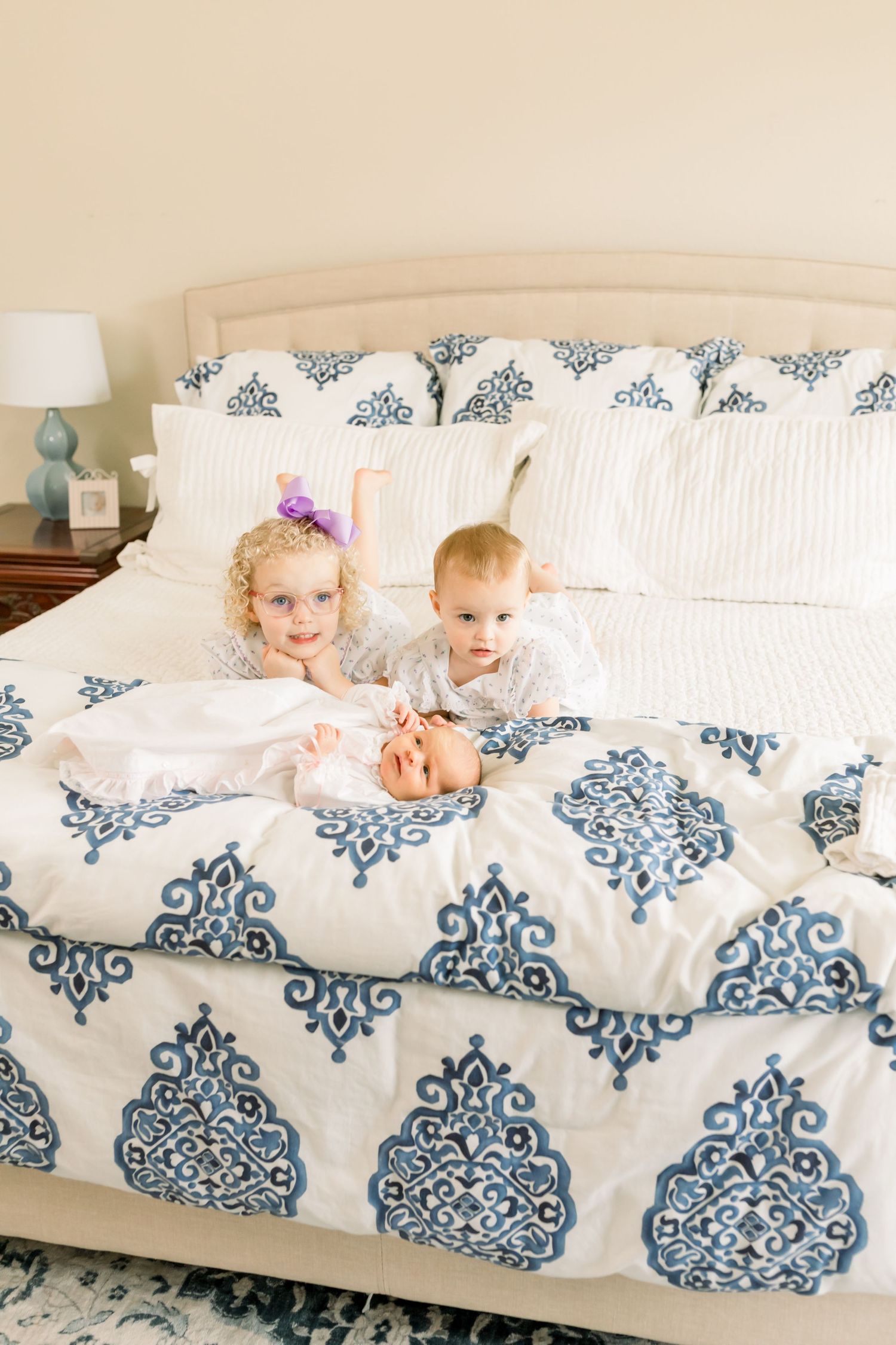 Children playing together on a bed with decorative blue and white bedding.