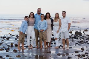 Family group portrait on rocky beach at sunset.