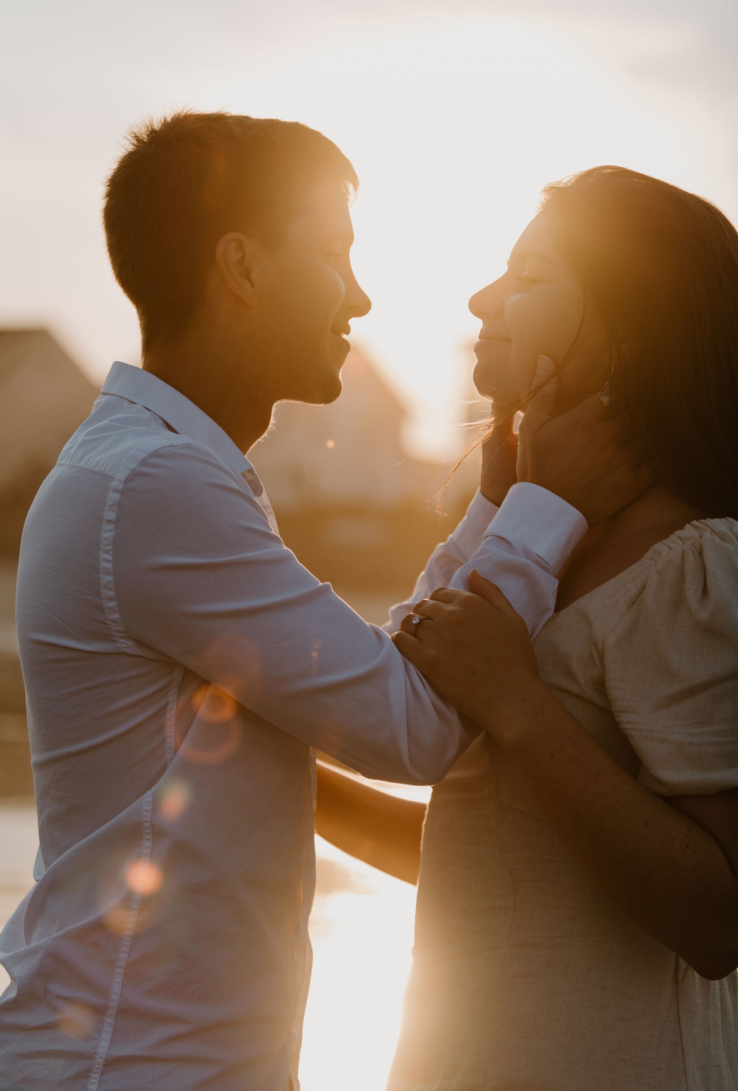 Couple in profile against sunset sky sharing tender moment.