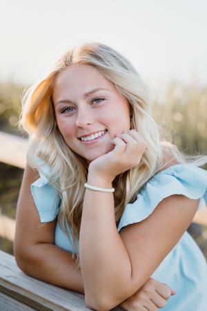 Portrait of person in light blue ruffled dress smiling outdoors.