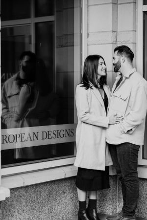 A couple shares a tender moment outside a storefront with European Designs signage.