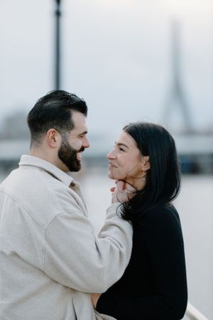 A couple shares an intimate moment with the Eiffel Tower visible in the background.