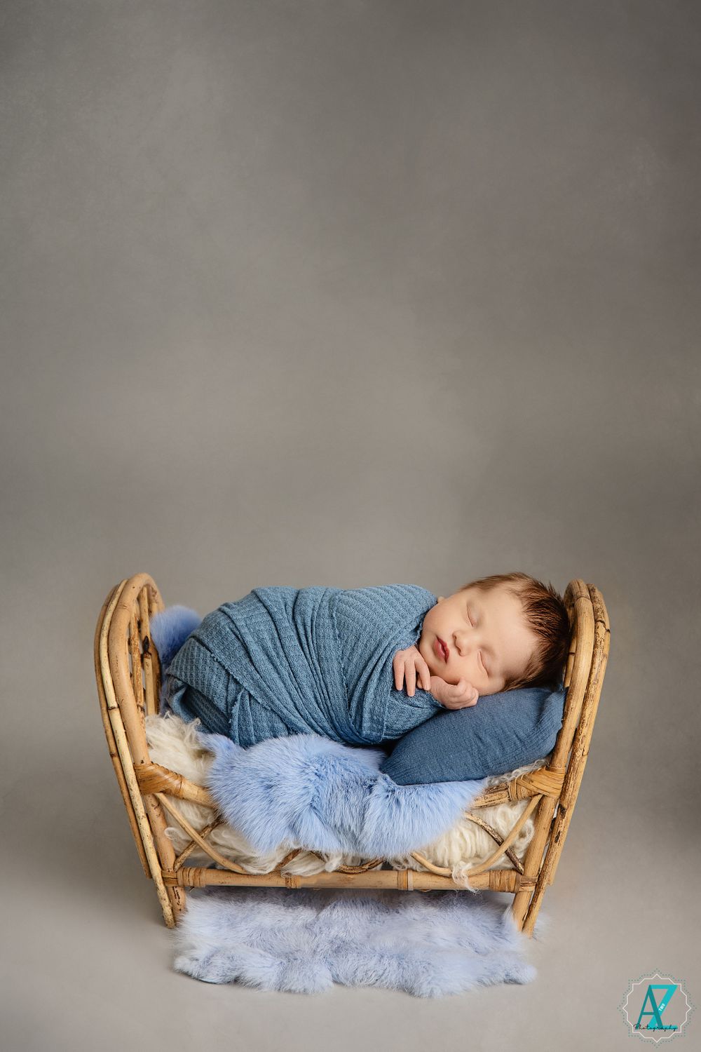 Sleeping baby wrapped in blue swaddle resting peacefully in wooden curved bed with soft blue accents.