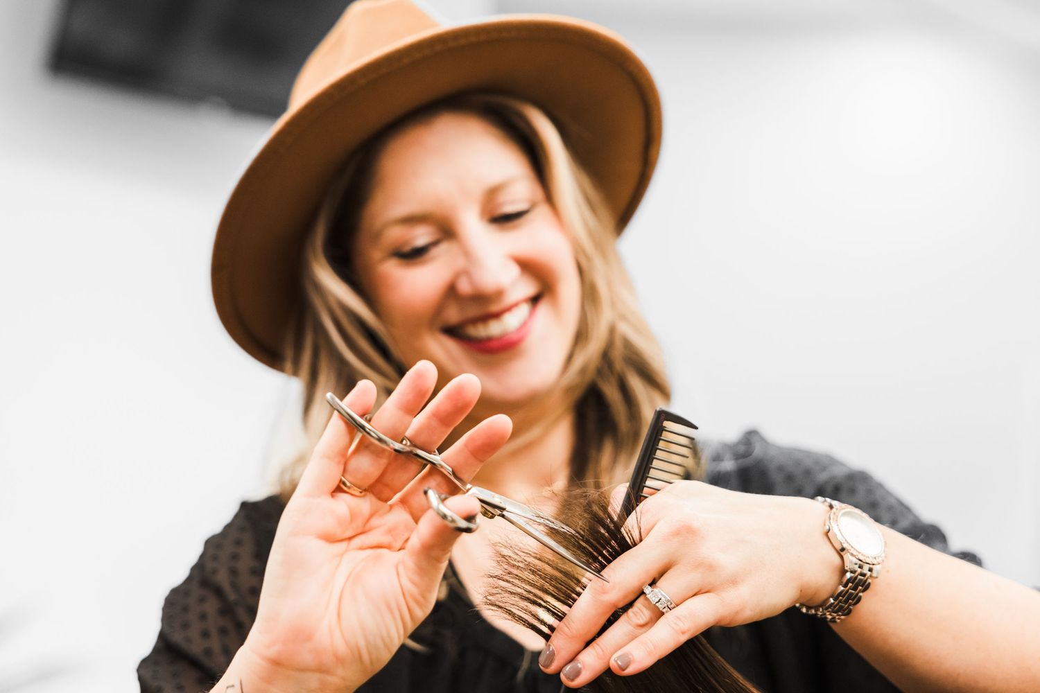 stylist with wide rimmed hat cutting hair