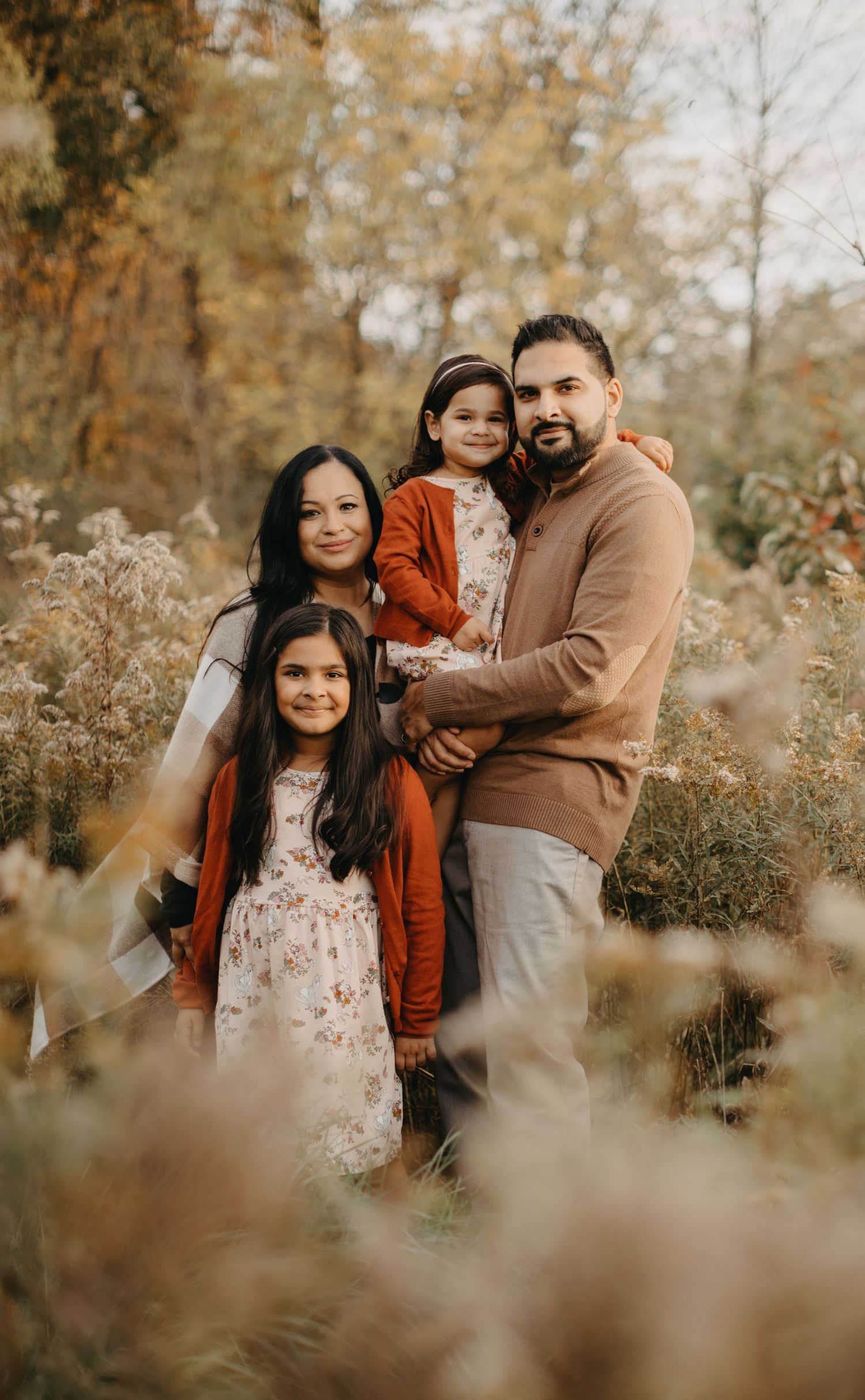 Family portrait in autumn setting with golden foliage and warm tones.