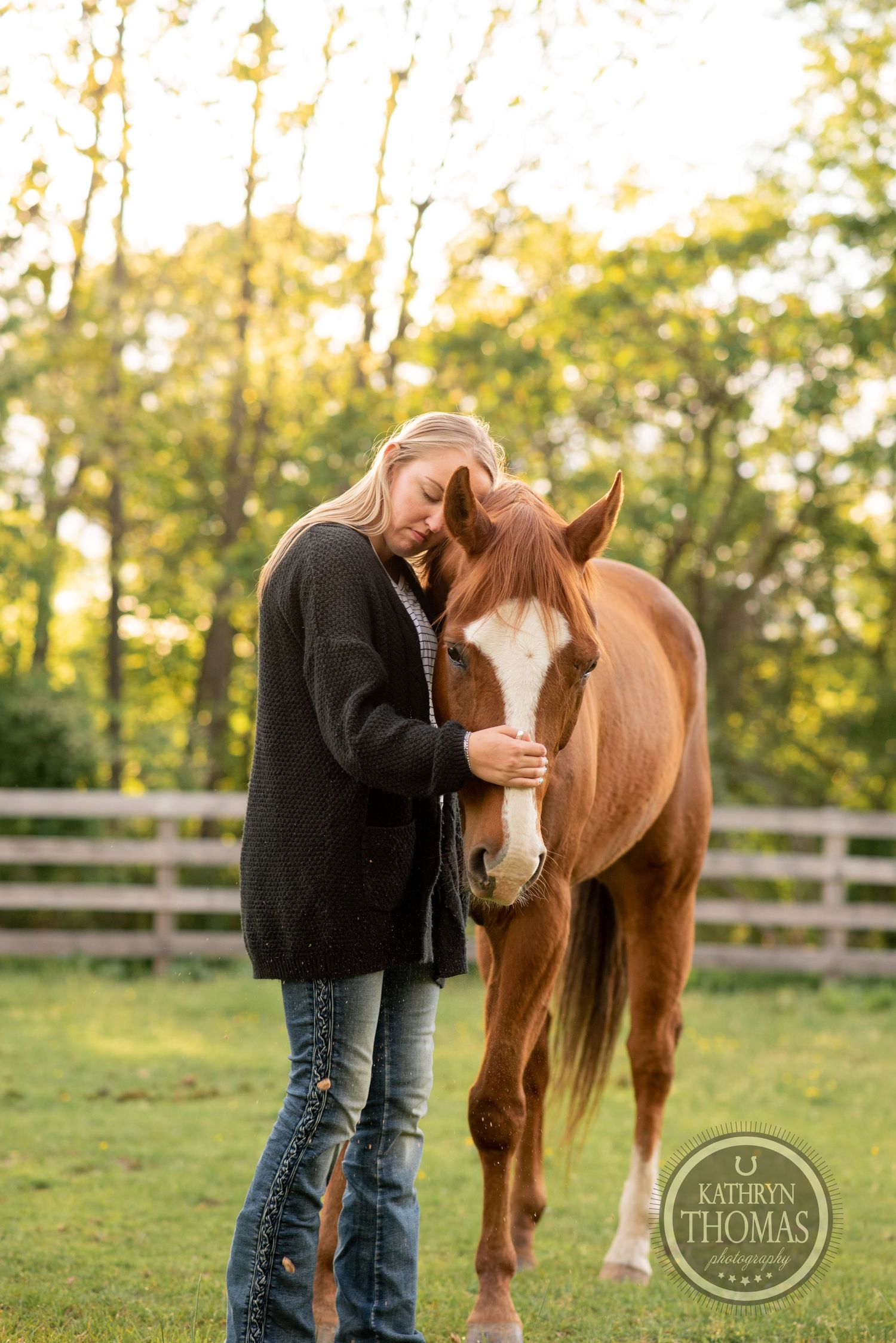 Intimate moment between a chestnut horse with white blaze and person in black sweater at sunset.